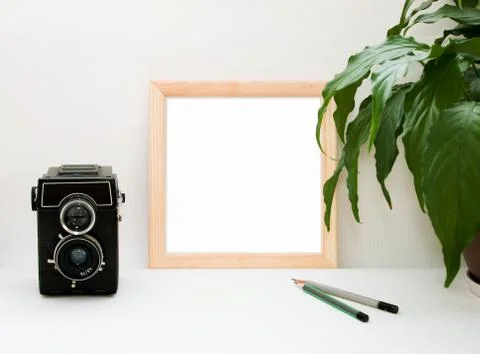 Mock up wooden frame, old camera, plant and pencils. Interior home square pos Stock Photos