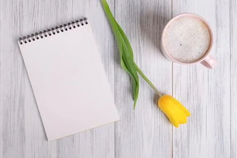Mockup of a blank notepad, a cup of coffee or cocoa and a yellow tulip Stock Photos