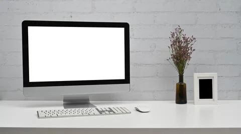 Mockup computer with blank screen on white table against brick wall. Home office Stock Photos