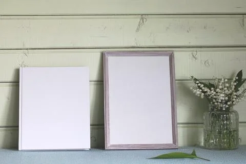 Mockup cottage. an empty frame and a book with an empty cover on the table .. Stock Photos