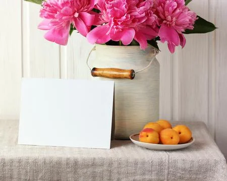 Mockup with an empty card on a table with pink peonies. Stock Photos