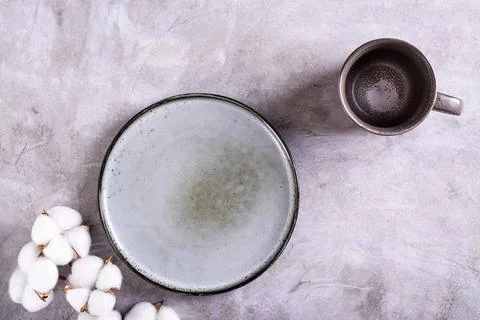 Mockup of empty ceramic plate, cup and cotton branch on gray background top.. Stock Photos