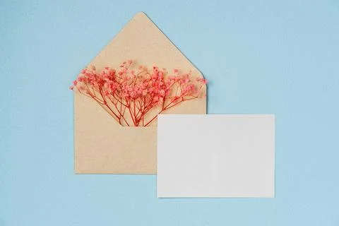 Mockup of flowers in envelope with empty white paper list on blue background  Foto stock