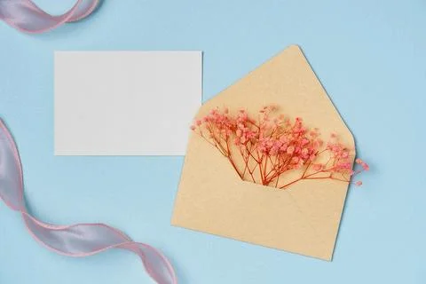 Mockup of flowers in envelope with empty white paper list on blue backgroun.. Stock Photos