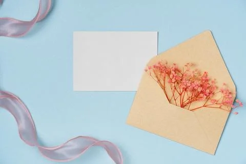Mockup of flowers in envelope with empty white paper list on blue backgroun.. Stock Photos