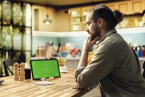 Mockup green screen on tablet screen in the kitchen at wooden table 스톡 사진