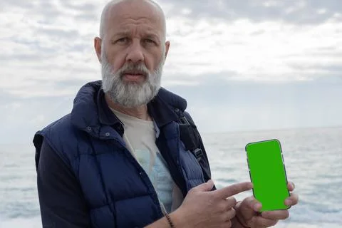 Mockup image of a grey-haired bearded man pointing his finger at a phone Stock Photos