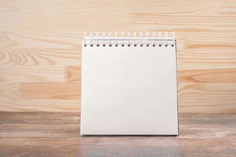Mockup image. square notebook with blank page stands upright on wood table ag Stock Photos