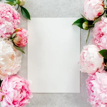 Mockup invitation, blank paper greeting card and peonies on gray stone table Stock Photos