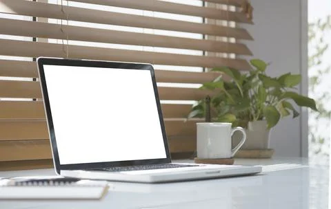 Mockup laptop computer, coffee cup, notebook and potted plant on white tabl.. Stock Photos