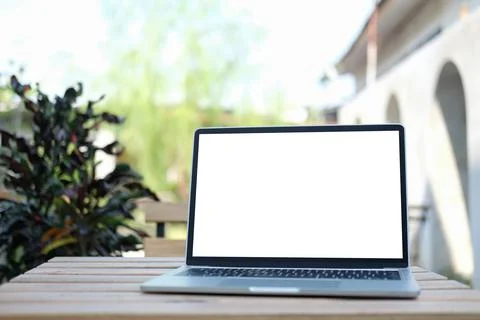 Mockup laptop computer with empty screen on wooden table at outdoor. Blank sc Stock Photos