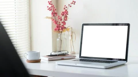Mockup laptop with empty display, coffee cup, books white table.. Stock Photos