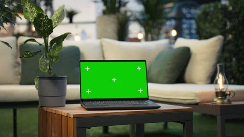 Mockup laptop with isolated screen on rooftop lounge table next to lush plants Stock Footage 345166069
