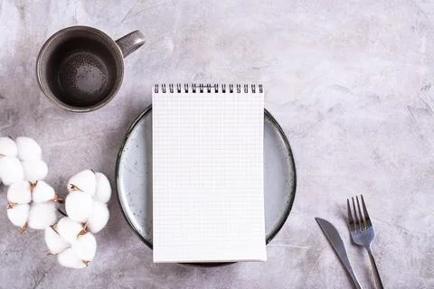 Mockup of a notebook on a plate, an empty cup and a branch of cotton on a g.. Stock Photos