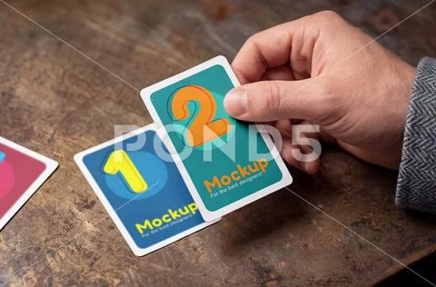 Mockup of playing cards on a table and in a hand PSD Template