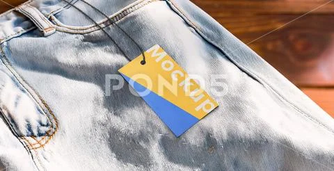 Mockup of rectangular paper tag and string on jean pants with wooden background PSD Template