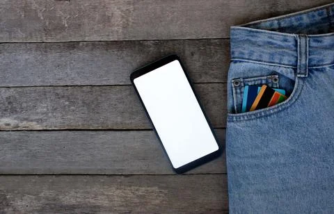 Mockup Smartphone with empty screen and credit cards in pocket jeans on wooden Stock Photos