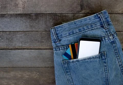 Mockup Smartphone with empty screen and credit cards in pocket jeans on wooden Stock Photos