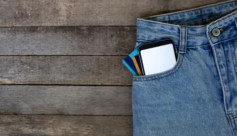 Mockup Smartphone with empty screen and credit cards in pocket jeans on wooden Stock-Fotos