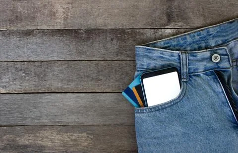 Mockup Smartphone with empty screen and credit cards in pocket jeans on wooden Stock Photos