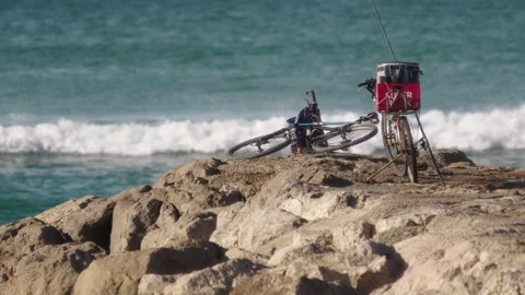 Mockup. Two bikes on the reef and leaning fishing rods wave in the background Stock Footage 231477170