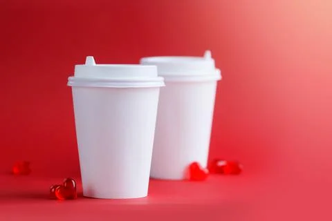Mockup of two coffee cups on a red background with glass hearts. Layout. Stock Photos