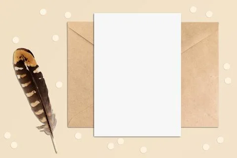Mockup of vertical postcard on a table with envelope and feather elements. Bo Stock Photos
