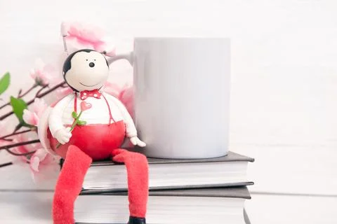 Mockup of a white ceramic mug on a table with books and flowers Photos