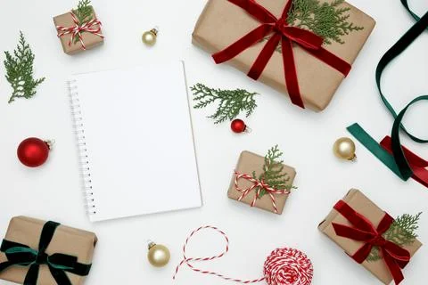 Mockup of white notebook surrounded by wrapped Christmas gifts and thuja bran Stock Photos