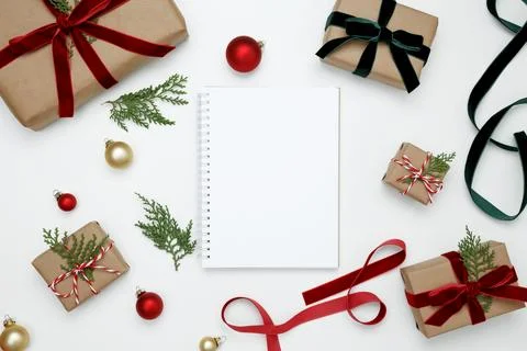 Mockup of white notebook surrounded by wrapped Christmas gifts and thuja bran Stock Photos
