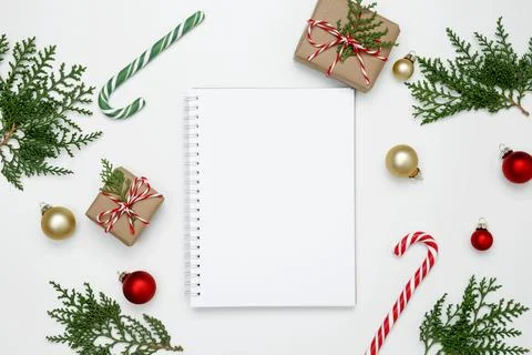 Mockup of white notebook surrounded by wrapped Christmas gifts and thuja bran Stock Photos