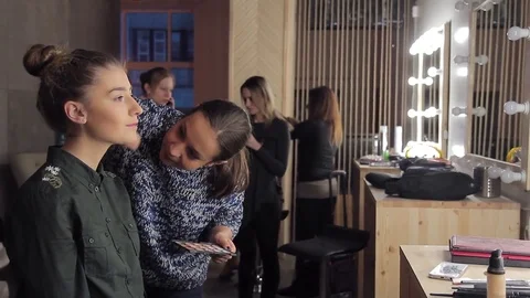 Model and make-up artist applying brush to model's face in makeup room Stock Footage 72600837