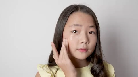 The model is applying a cream or product to her face with her finger Stock Footage 319824083