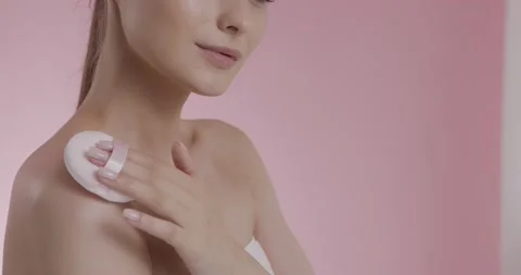 Model applying powder on bare shoulders and neck with puff Stock Footage 158754951