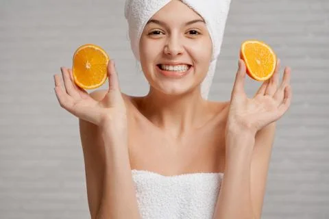 Model with bare shoulders holding two pieces of orange. Stock Photos