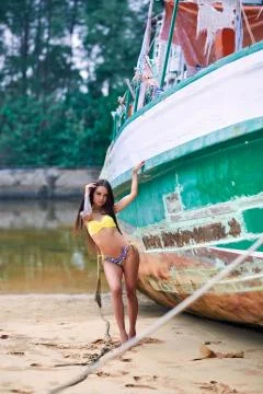 Model in bikini posing with old abandoned fishing boat Stock Photos