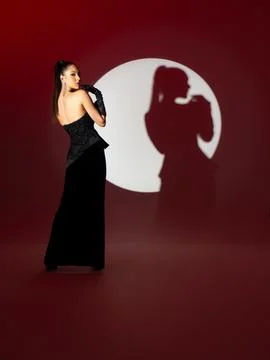 The model in the black dress is posing standing up in the studio. Stock Photos