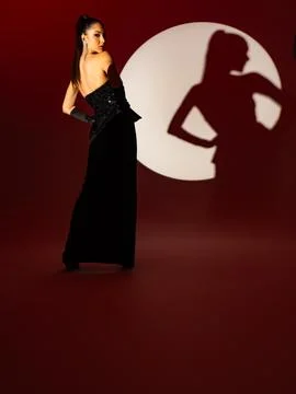 The model in the black dress is posing standing up in the studio. Stock Photos