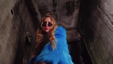 Model in blue fur coat walks in dark room. posing fashion Stock Footage 303364385
