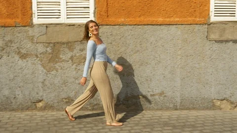 Model with Blue Long Sleeved Blouse Smiling and Walking Along Sidewalk Video stock 115842504