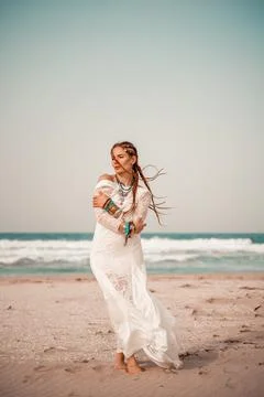 Model in boho style in a white long dress and silver jewelry on the beach. Her Stock Photos