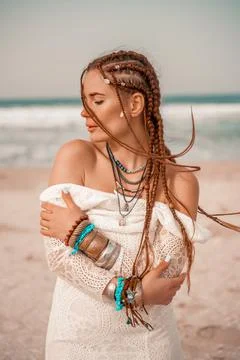 Model in boho style in a white long dress and silver jewelry on the beach. Her Stock Photos