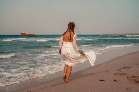 Model in boho style in a white long dress and silver jewelry on the beach. Her Stock Photos