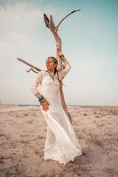 Model in boho style in a white long dress and silver jewelry on the beach. Her Stock Photos