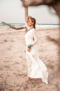 Model in boho style in a white long dress and silver jewelry on the beach. Her Stock Photos
