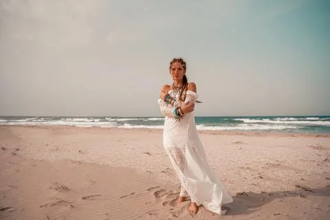 Model in boho style in a white long dress and silver jewelry on the beach. Her Stock Photos