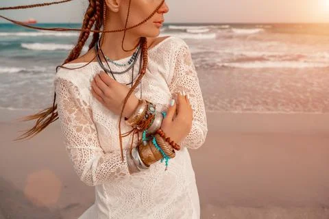 Model in boho style in a white long dress and silver jewelry on the beach. Her Stock Photos
