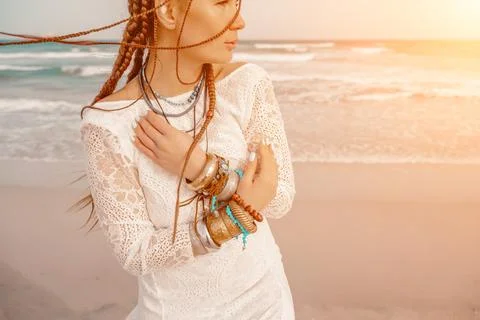 Model in boho style in a white long dress and silver jewelry on the beach. Her Stock Photos