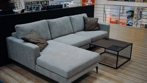Model of a comfortable gray sofa with two brown pillows in a shopping center Stock Footage 231507767