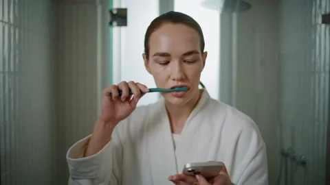 Model daily cleaning teeth using smartphone closeup. Pretty woman doing dental Stock Footage 278466490